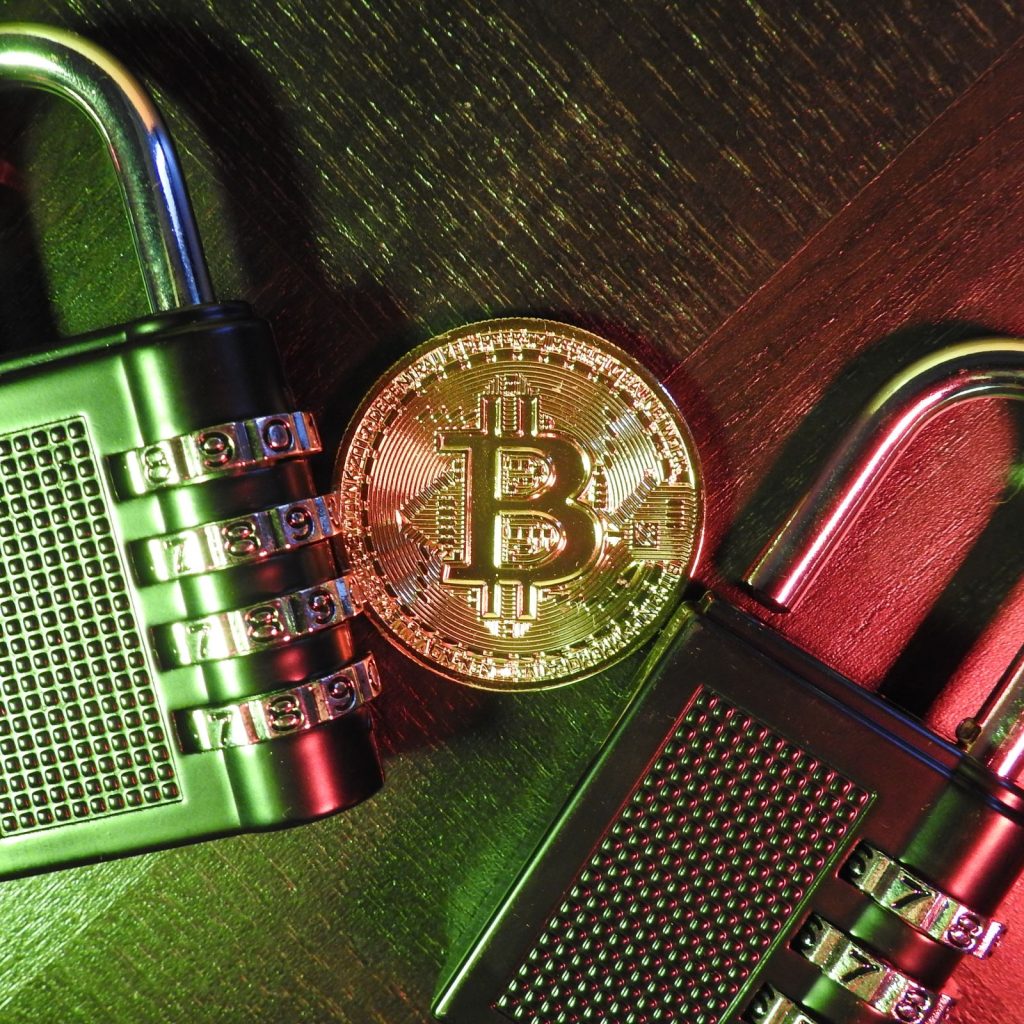 Gold coin and padlocks on wooden surface, symbolizing secured crypto collateral